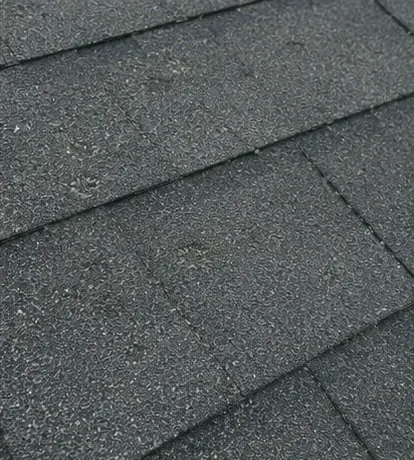 Close-range view of hail impact damage on asphalt shingles